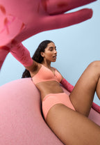 Zijde van vrouw die de soft bh en slip met glansband in de kleur peach pink van het merk Naturana draagt