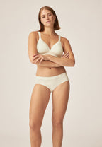 Voorzijde van vrouw die de soft bh met glansband en slip met glansband in de kleur ecru van het merk Naturana draagt