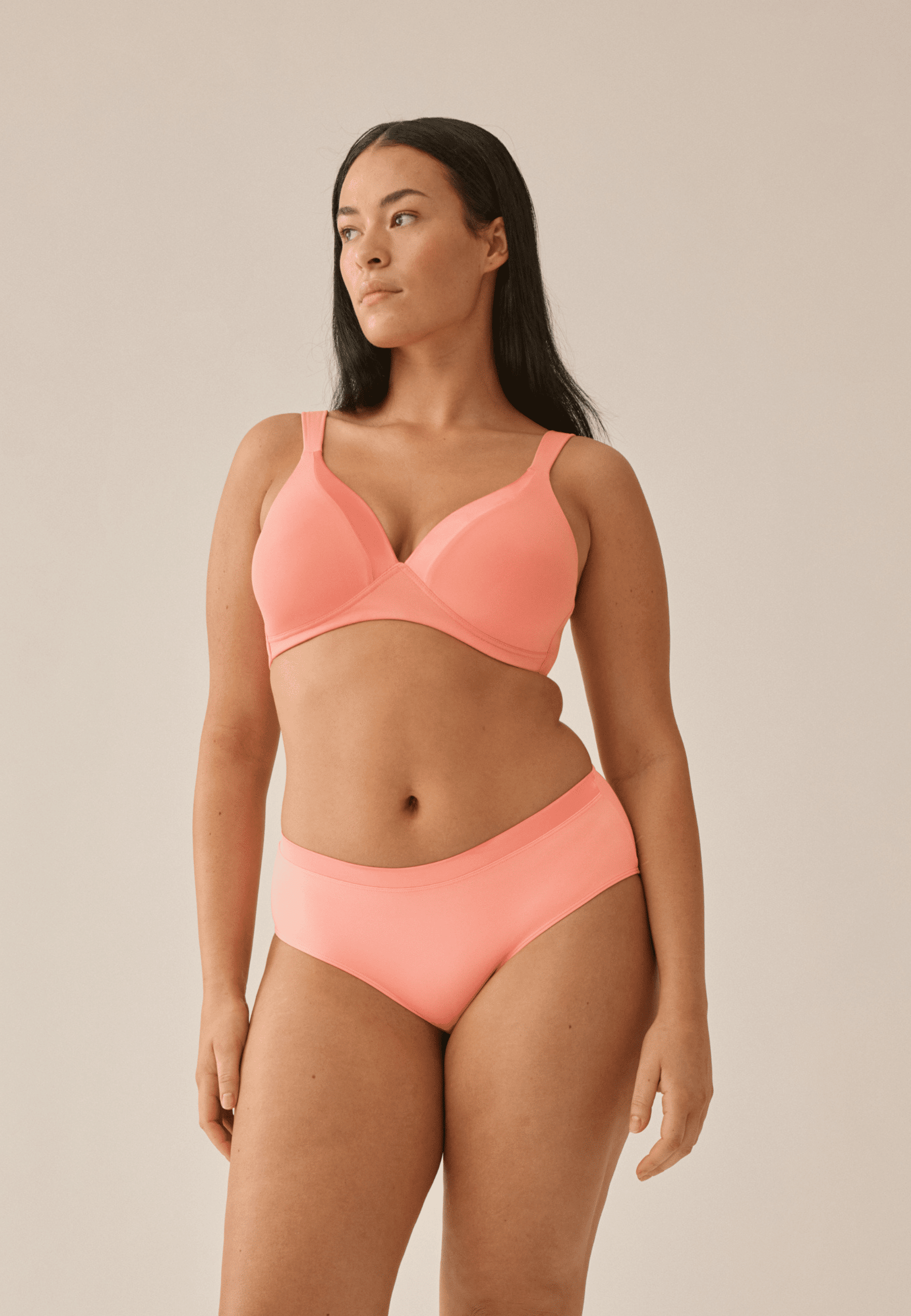 Voorzijde van vrouw die de soft bh met glansband en slip met glansband in de kleur peach pink van het merk Naturana draagt