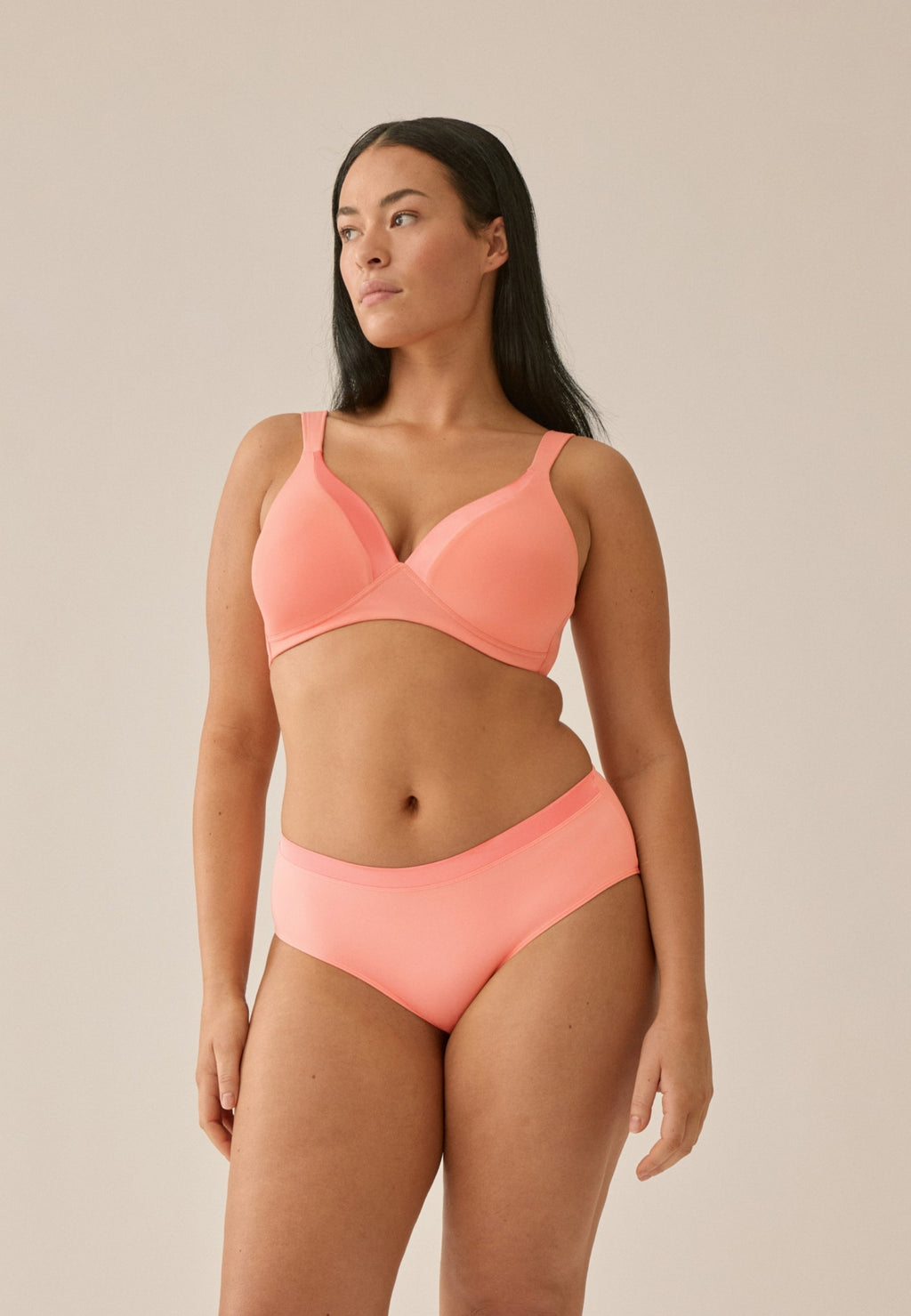Voorzijde van vrouw die de soft bh en slip met glansband in de kleur peach pink van het merk Naturana draagt