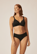 Voorzijde van vrouw die de soft bh met glansband en slip met glansband in de kleur zwart van het merk Naturana draagt