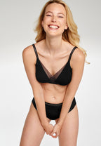 Voorzijde van vrouw die de soft bh en slip met mesh detail in de kleur zwart van het merk Naturana draagt
