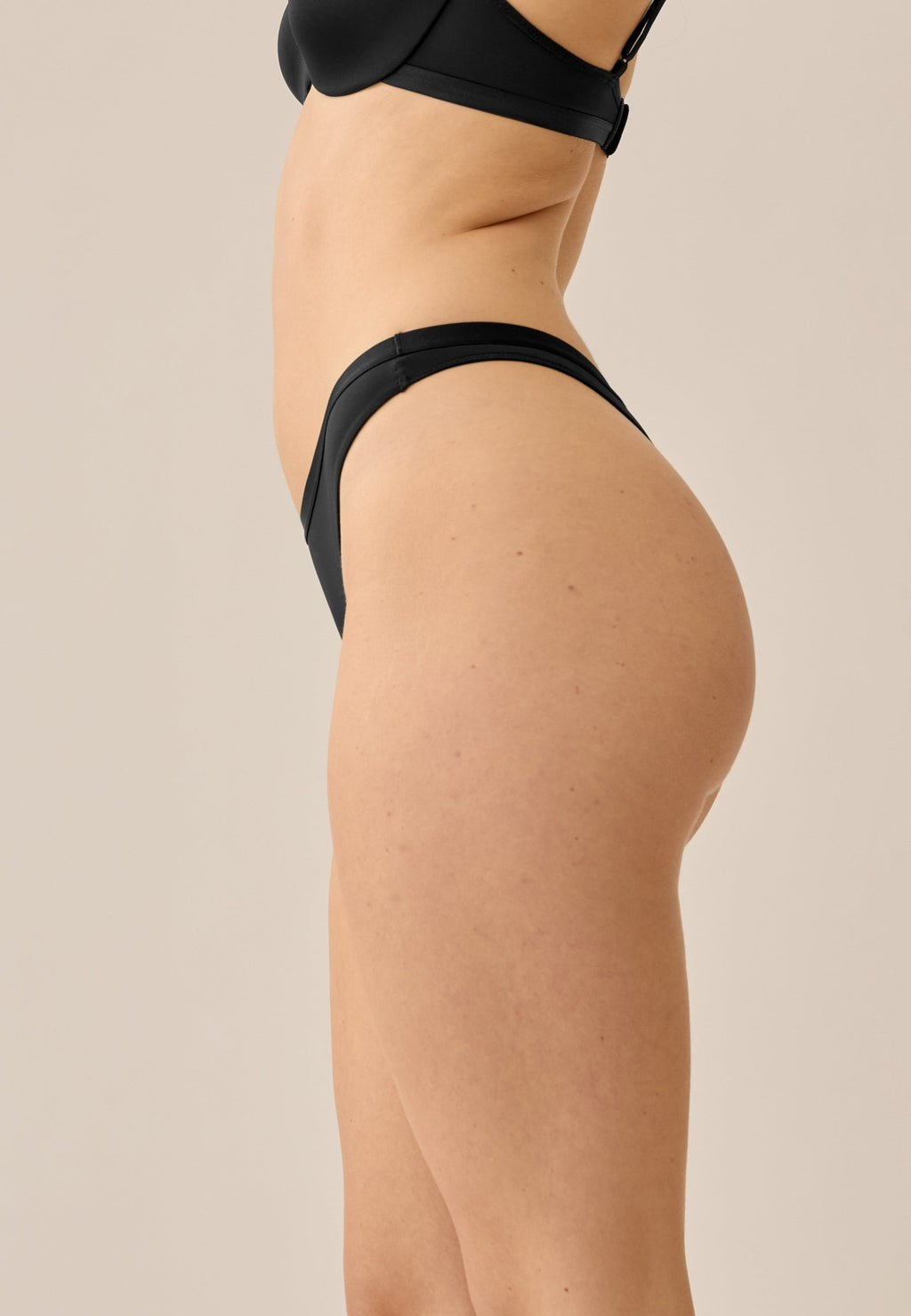 Zijde van vrouw die de string in de kleur zwart van het merk Naturana draagt