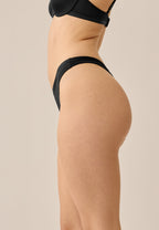 Zijde van vrouw die de string in de kleur zwart van het merk Naturana draagt