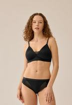 Voorzijde van vrouw die de voorgevormde soft bh met mesh detail en slip met mesh detail in de kleur zwart van het merk Naturana draagt
