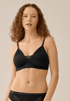 Voorzijde van vrouw die de voorgevormde soft bh met mesh detail in de kleur zwart van het merk Naturana draagt