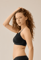 Zijde van vrouw die de voorgevormde soft bh met mesh detail in de kleur zwart van het merk Naturana draagt